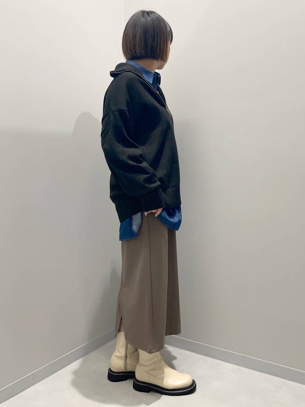 ブラック系のニット/セーター、ブルー系のシャツ/ブラウス、ブラウン系のスカートを着用したレディースの秋コーディネートの3枚目の写真