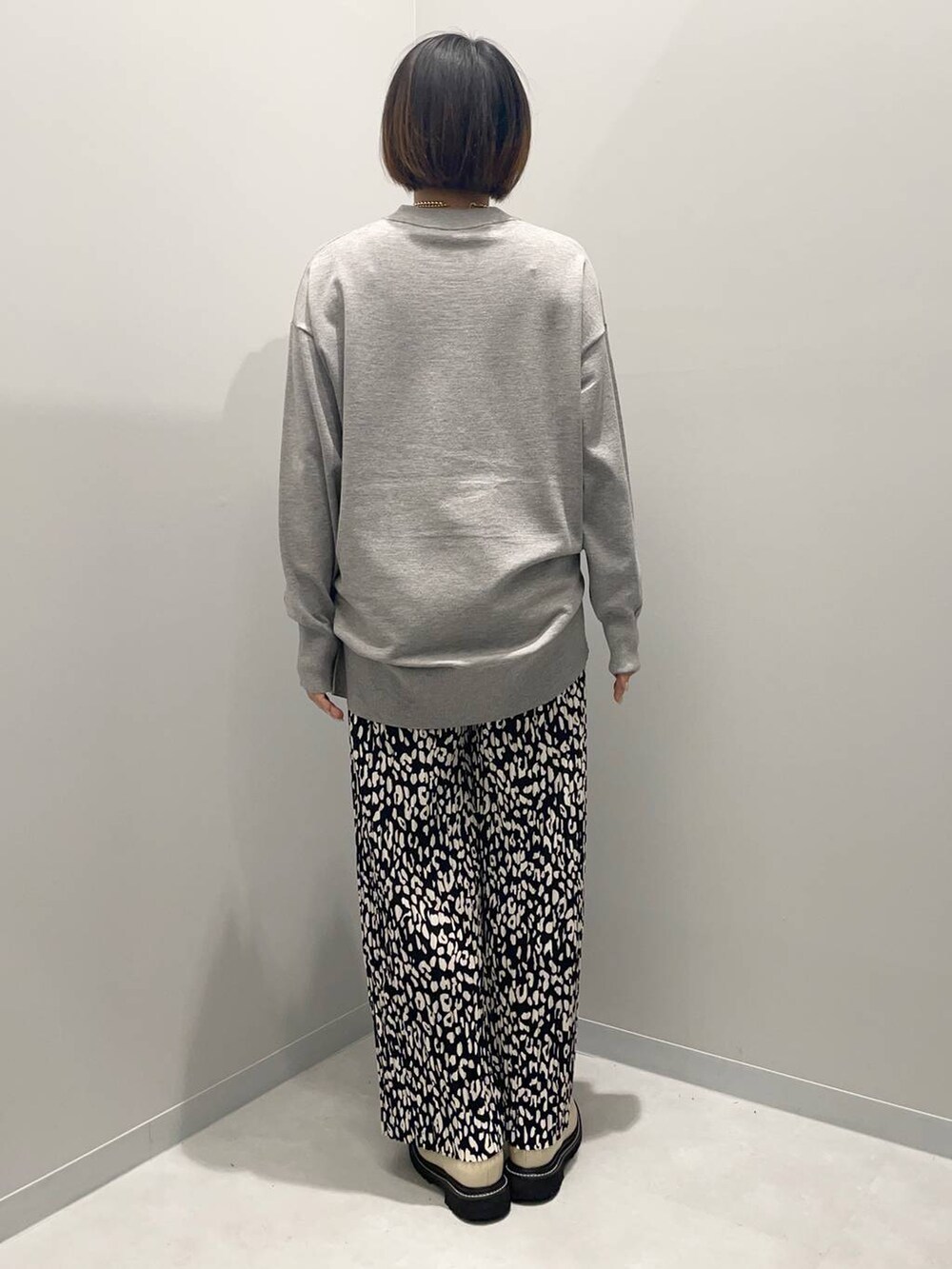 グレー系のニット/セーター、グレー系のその他パンツ、イエロー系のネックレスを着用したレディースの秋コーディネートの4枚目の写真