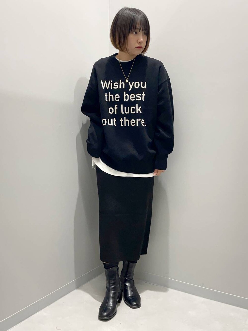 ブラック系のニット/セーター、ホワイト系のTシャツ/カットソー、ブラック系のスカートを着用したレディースの秋コーディネートの2枚目の写真
