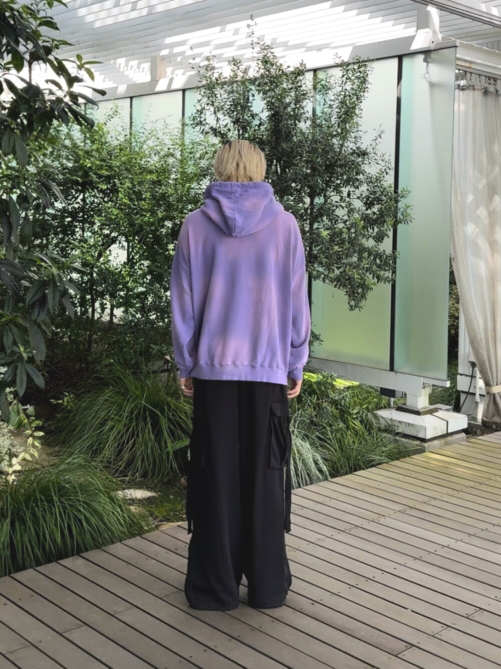 パープル系のパーカー、ブラック系のカーゴパンツを着用したメンズの秋コーディネートの2枚目の写真