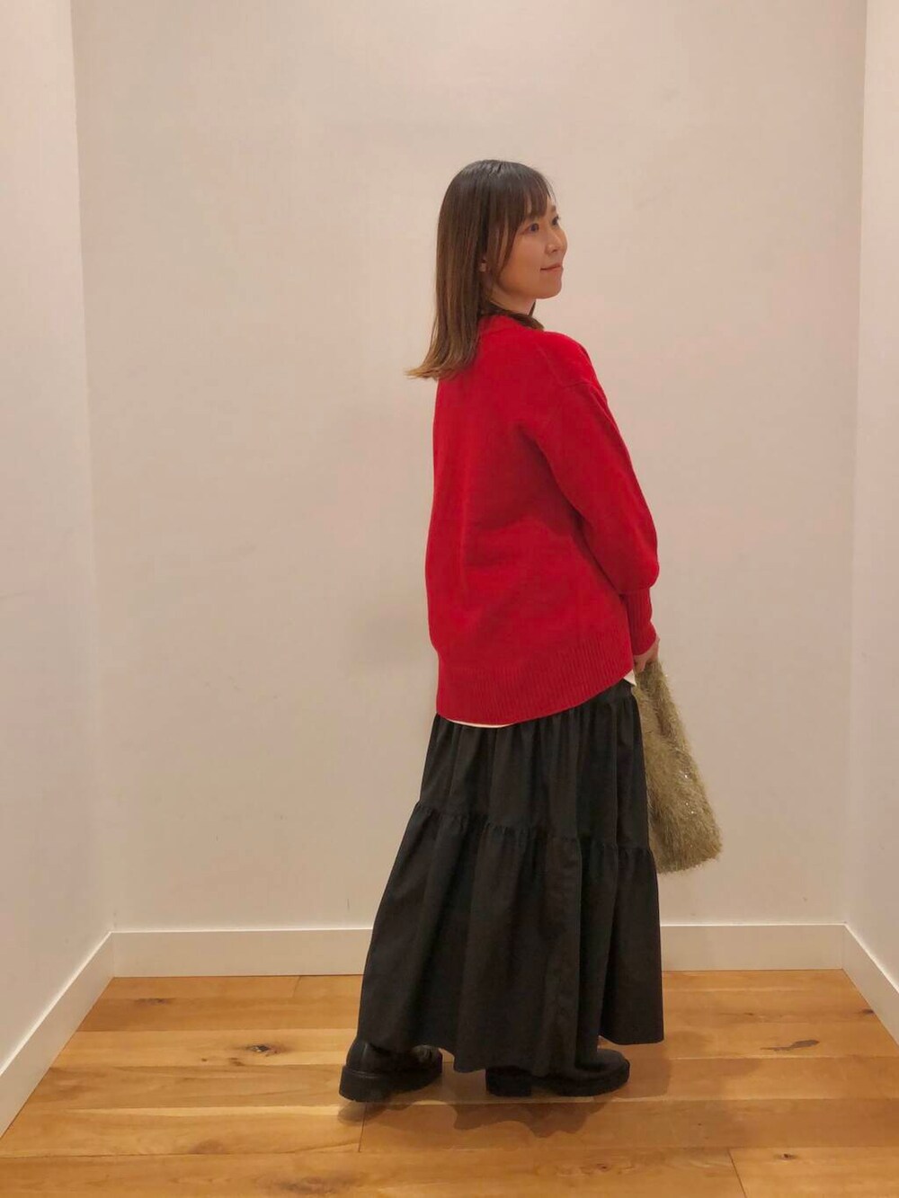 レッド系のニット/セーター、ホワイト系のTシャツ/カットソー、ブラック系のスカートを着用したレディースの冬コーディネートの4枚目の写真