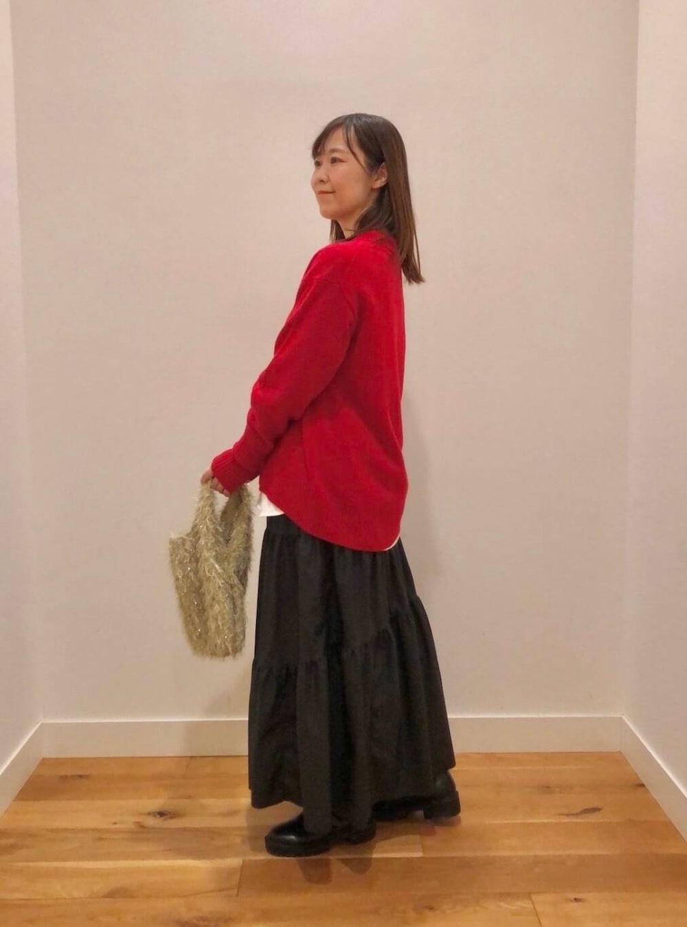 レッド系のニット/セーター、ホワイト系のTシャツ/カットソー、ブラック系のスカートを着用したレディースの冬コーディネートの2枚目の写真