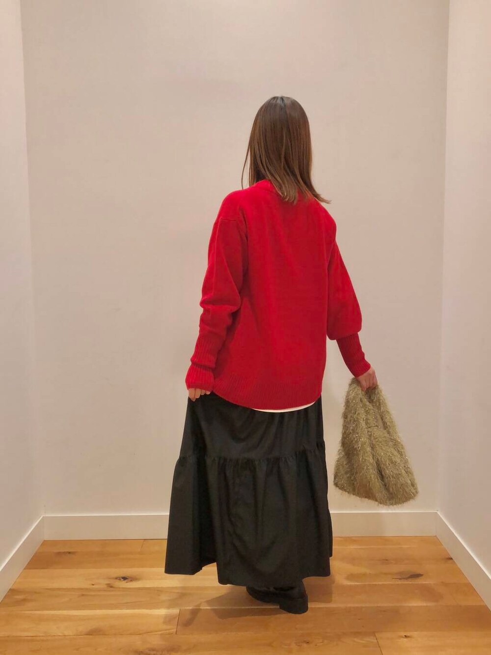 レッド系のニット/セーター、ホワイト系のTシャツ/カットソー、ブラック系のスカートを着用したレディースの冬コーディネートの3枚目の写真