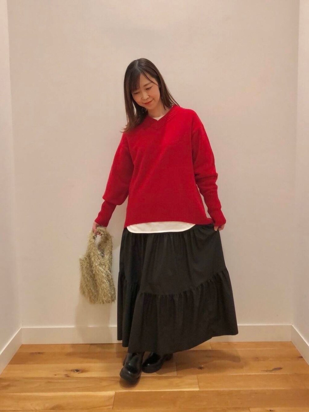 レッド系のニット/セーター、ホワイト系のTシャツ/カットソー、ブラック系のスカートを着用したレディースの冬コーディネートの5枚目の写真