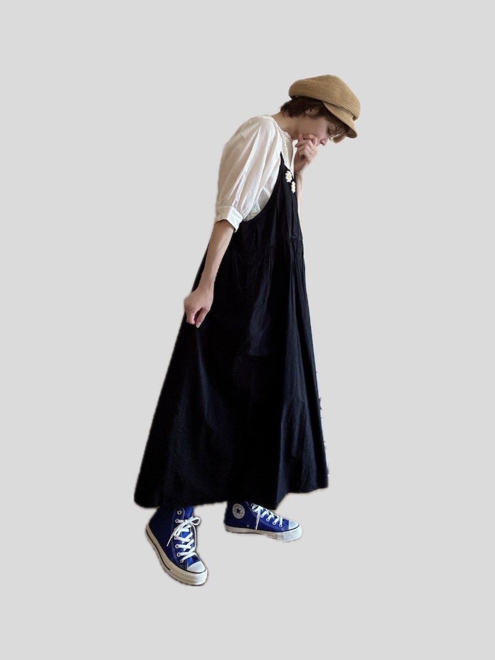 ブルー系のスニーカー、ブラック系のジャンパースカート、ホワイト系のブローチ/コサージュを着用したレディースの秋コーディネートの2枚目の写真