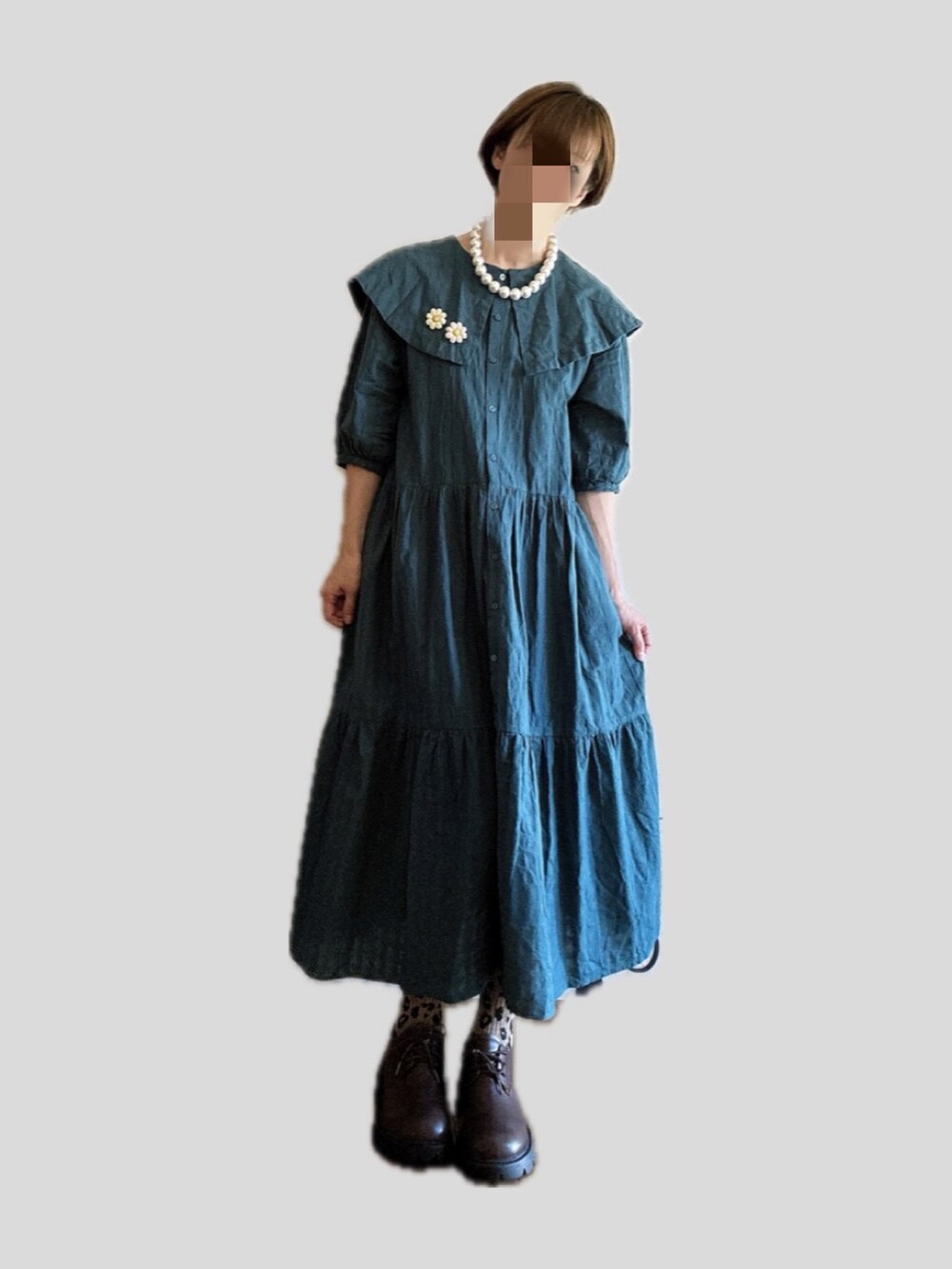 グリーン系のワンピース、ブラウン系のドレスシューズ、ホワイト系のブローチ/コサージュを着用したレディースの秋コーディネートの2枚目の写真