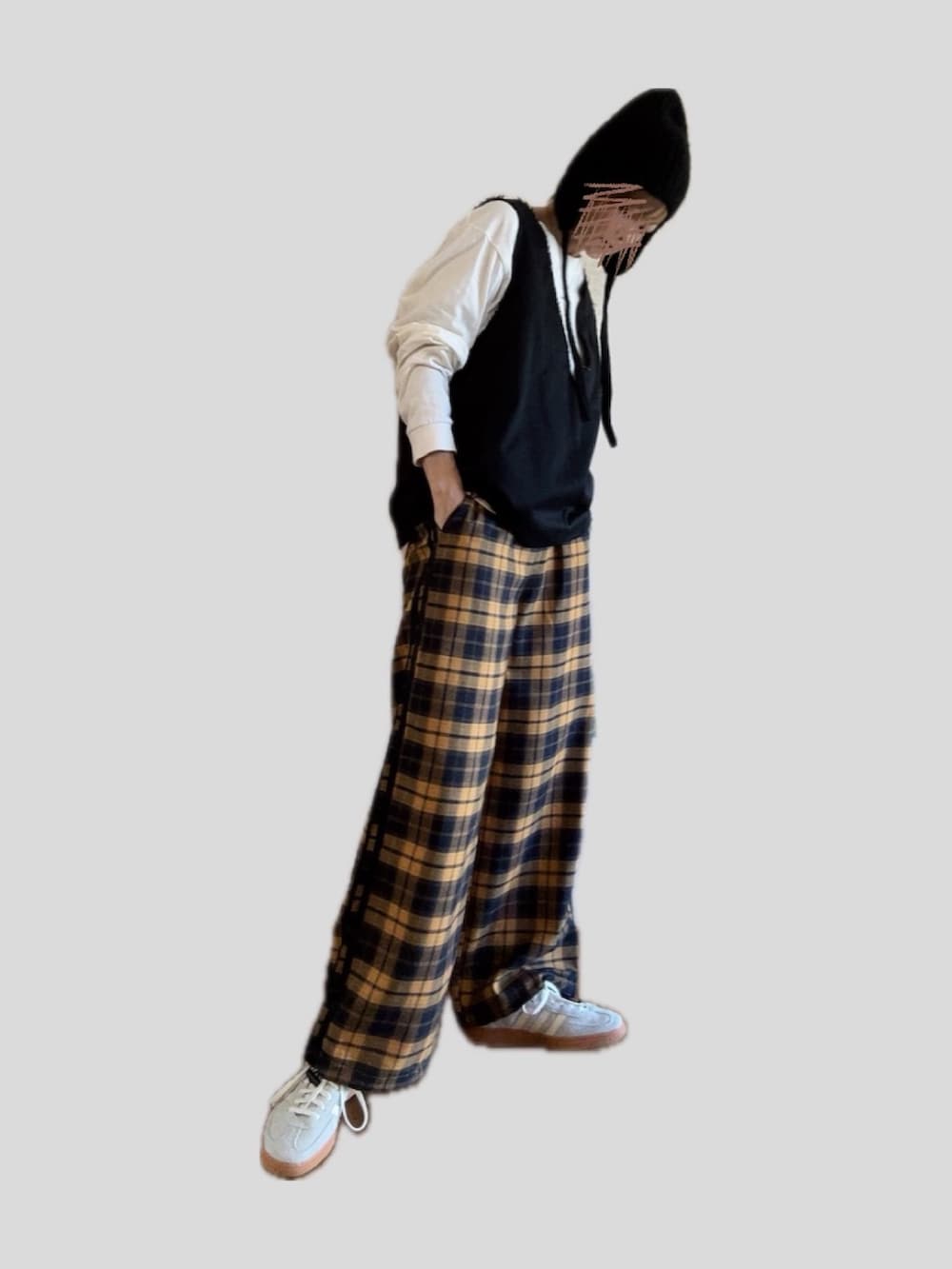 イエロー系のパンツ、グレー系のスニーカー、ブラック系のベストを着用したレディースの秋コーディネートの2枚目の写真