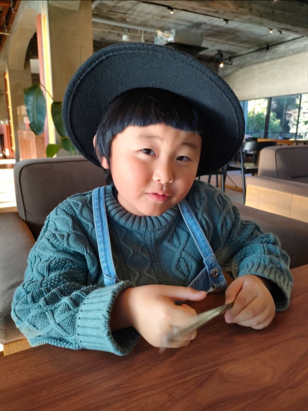 ブルー系のサロペット/オーバーオール、グリーン系のニット/セーター、ホワイト系のニット/セーターを着用したキッズの冬コーディネートの2枚目の写真