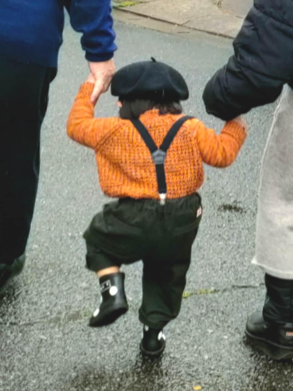 オレンジ系のニット/セーター、ブラック系のパンツ、ブラック系のレインシューズを着用したキッズの春コーディネートの3枚目の写真