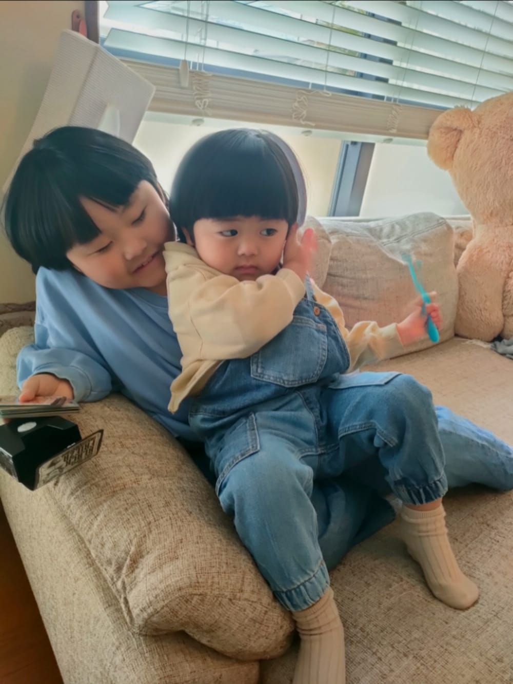 ブルー系のスウェット、ブルー系のデニムパンツ、ベージュ系のパーカーを着用したキッズの春コーディネートの2枚目の写真