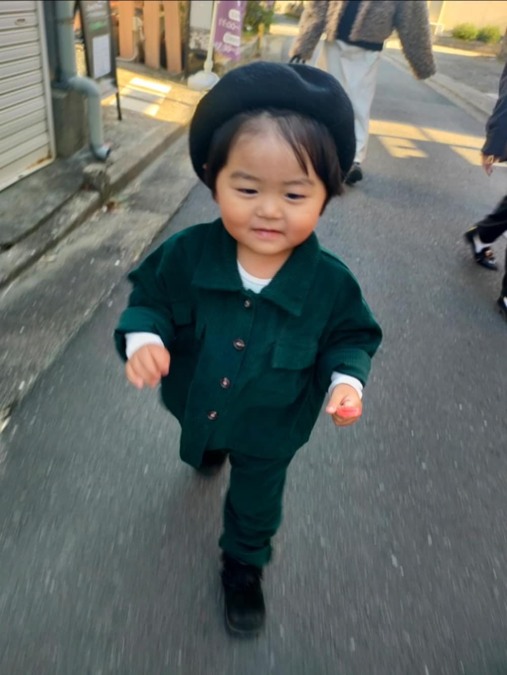 グリーン系のセットアップ、ブラック系のブーツ、ブラック系のハンチング/ベレー帽を着用したキッズの冬コーディネートの3枚目の写真