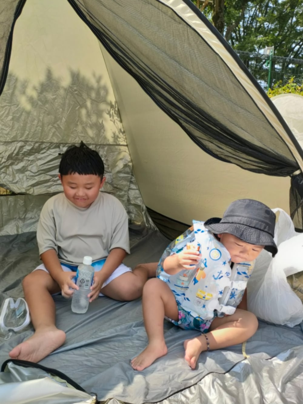 グレー系のTシャツ/カットソー、ブラック系のハット、ホワイト系のスイムグッズを着用したキッズの秋コーディネートの2枚目の写真