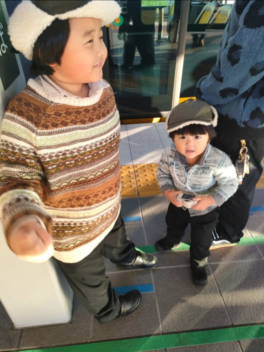 ブラウン系のニット/セーター、ブラック系のパンツ、ブラック系のローファーを着用したキッズの冬コーディネートの2枚目の写真