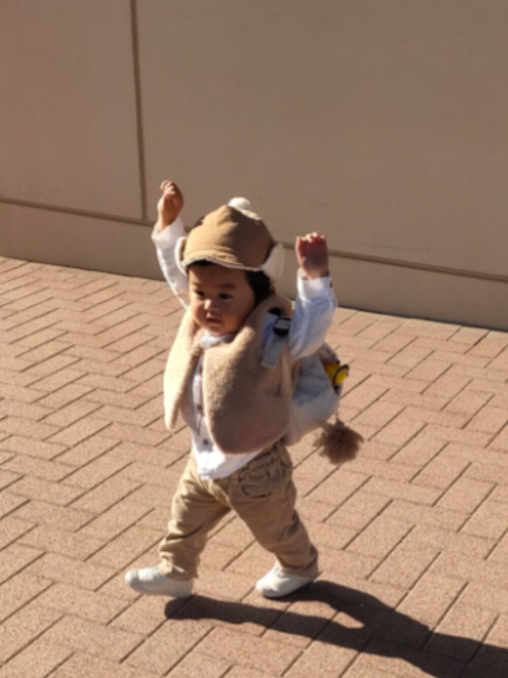 ベージュ系のベスト、ホワイト系のスニーカー、ベージュ系のパンツを着用したキッズの秋コーディネートの3枚目の写真