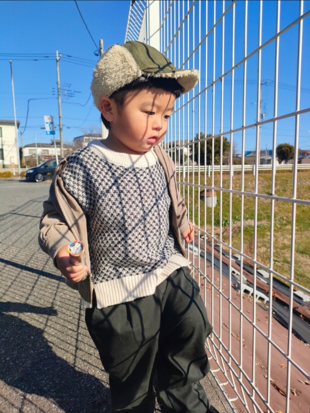 ホワイト系のカーディガン/ボレロ、ブラック系のパンツ、ブラック系のブーツを着用したキッズの冬コーディネートの2枚目の写真