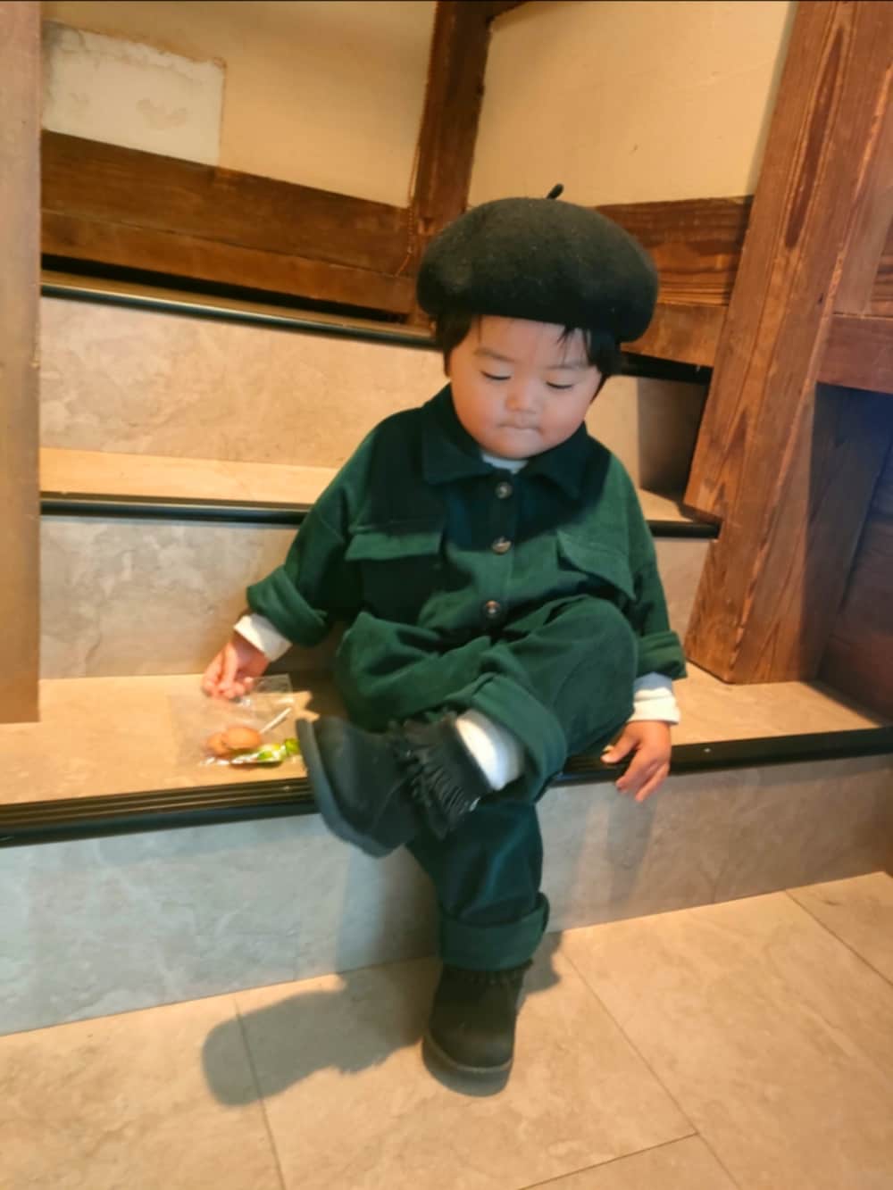 グリーン系のセットアップ、ブラック系のブーツ、ブラック系のハンチング/ベレー帽を着用したキッズの冬コーディネートの2枚目の写真