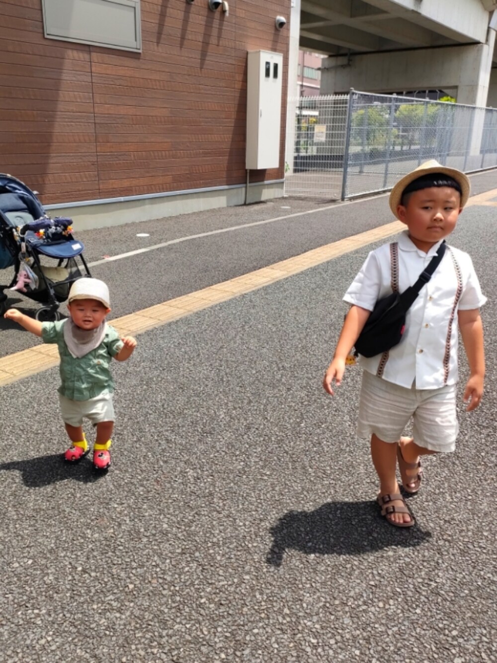 ブラック系のメッセンジャーバッグ、ホワイト系のシャツ/ブラウス、ベージュ系のパンツを着用したキッズの夏コーディネートの2枚目の写真