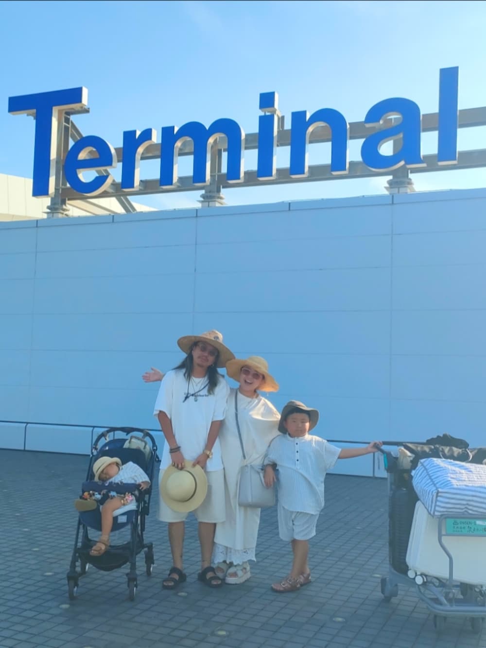 ホワイト系のセットアップ、ブラウン系のサンダル、ホワイト系のスーツケース/キャリーバッグを着用したキッズの夏コーディネートの5枚目の写真