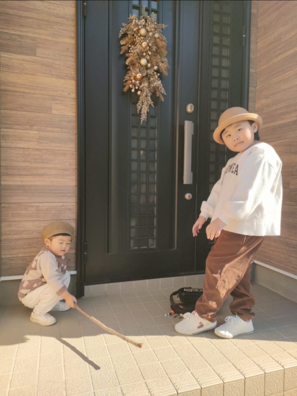 ブラウン系のカーディガン/ボレロ、ホワイト系のスニーカー、ブラウン系のセットアップを着用したキッズの冬コーディネートの2枚目の写真