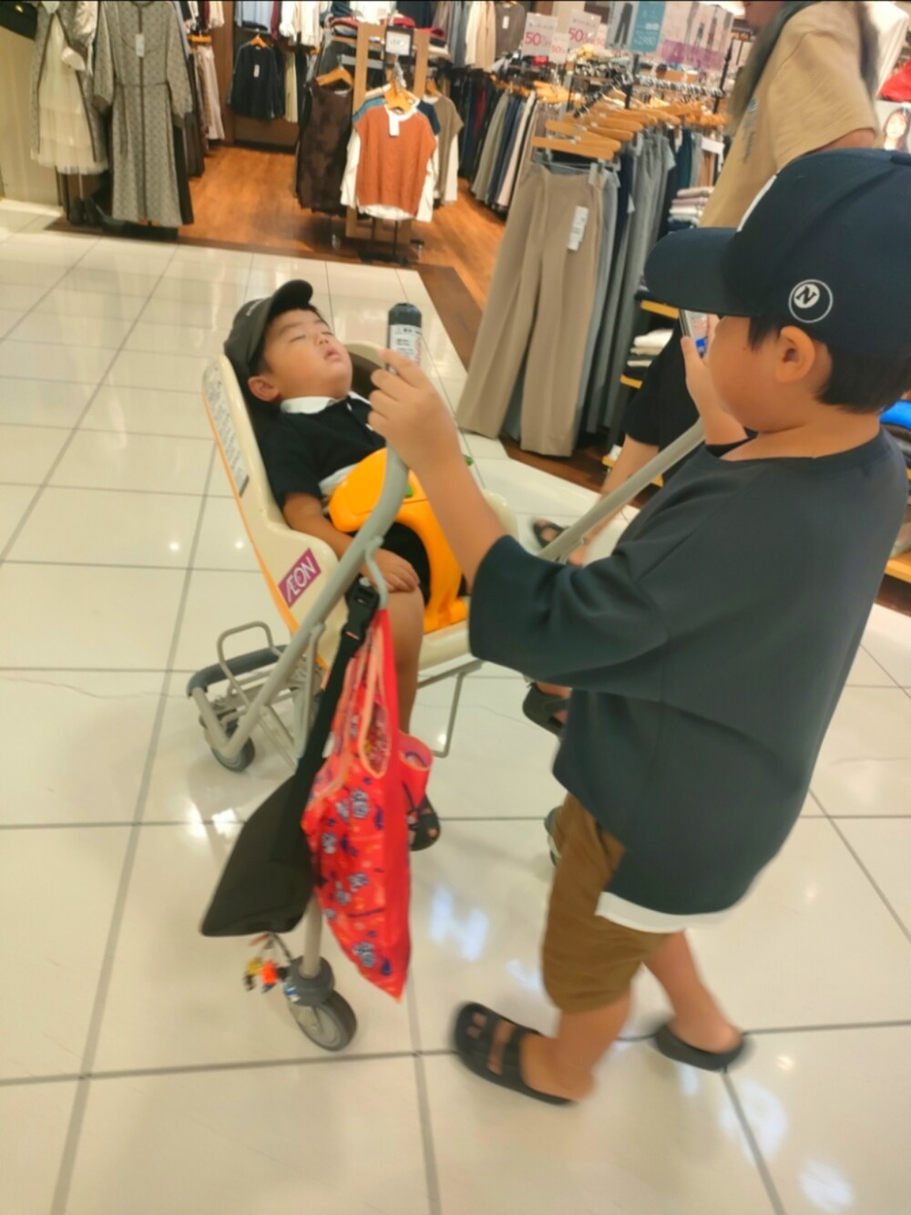 グレー系のTシャツ/カットソー、ブラウン系のパンツ、ブラック系のサンダルを着用したキッズの秋コーディネートの2枚目の写真