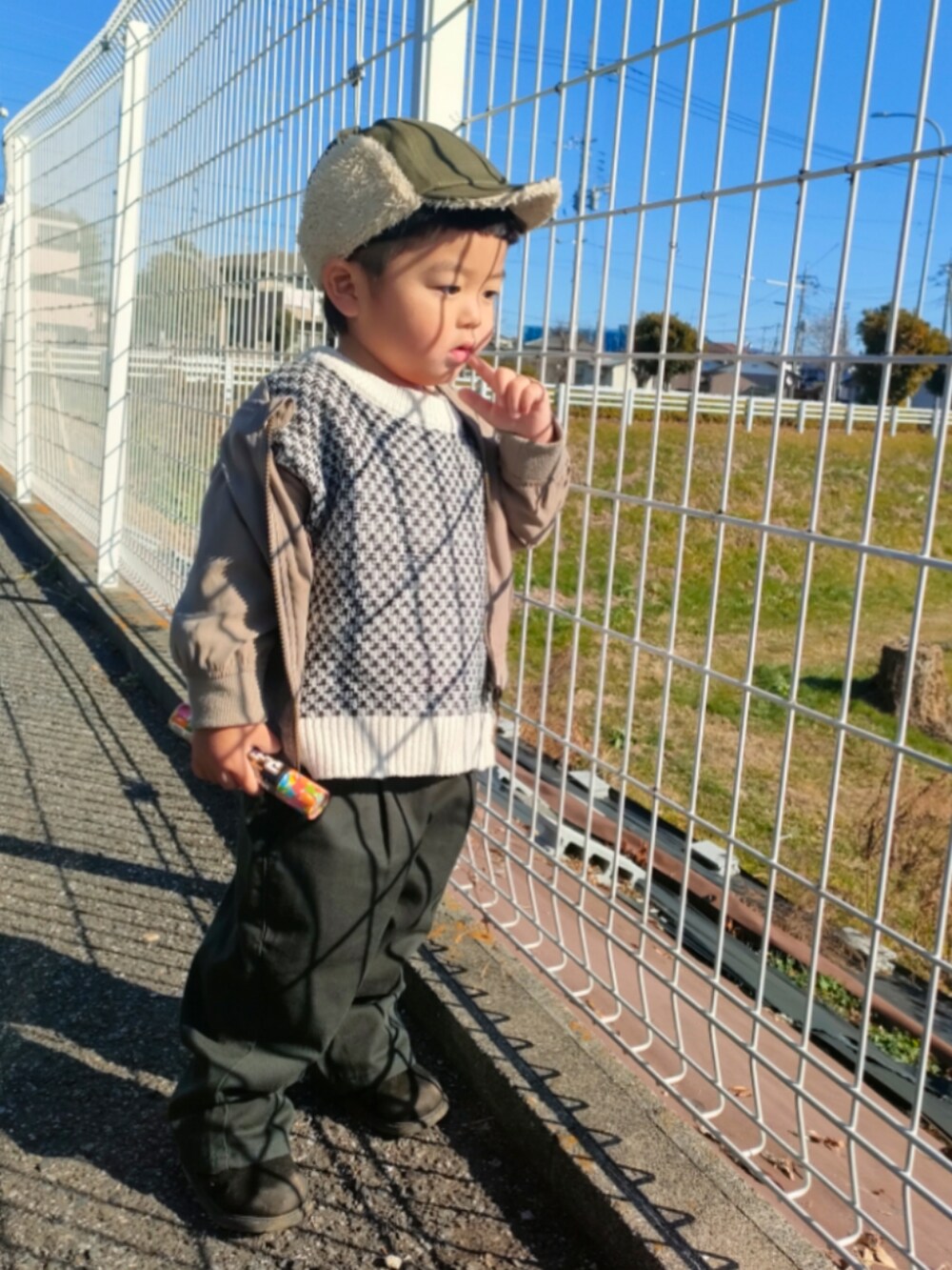 ホワイト系のカーディガン/ボレロ、ブラック系のパンツ、ブラック系のブーツを着用したキッズの冬コーディネートの3枚目の写真