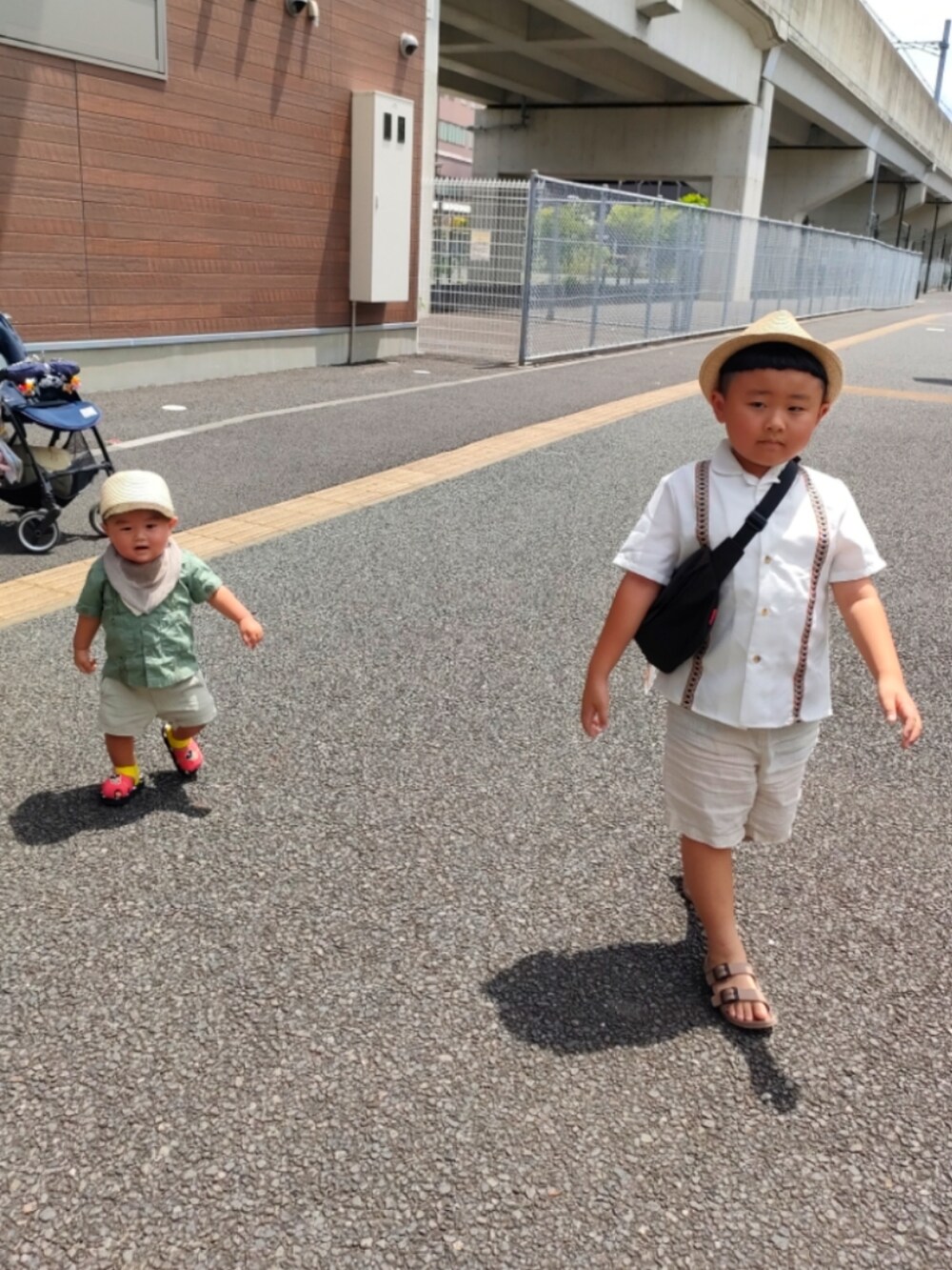 ブラック系のメッセンジャーバッグ、ホワイト系のシャツ/ブラウス、ベージュ系のパンツを着用したキッズの夏コーディネートの3枚目の写真