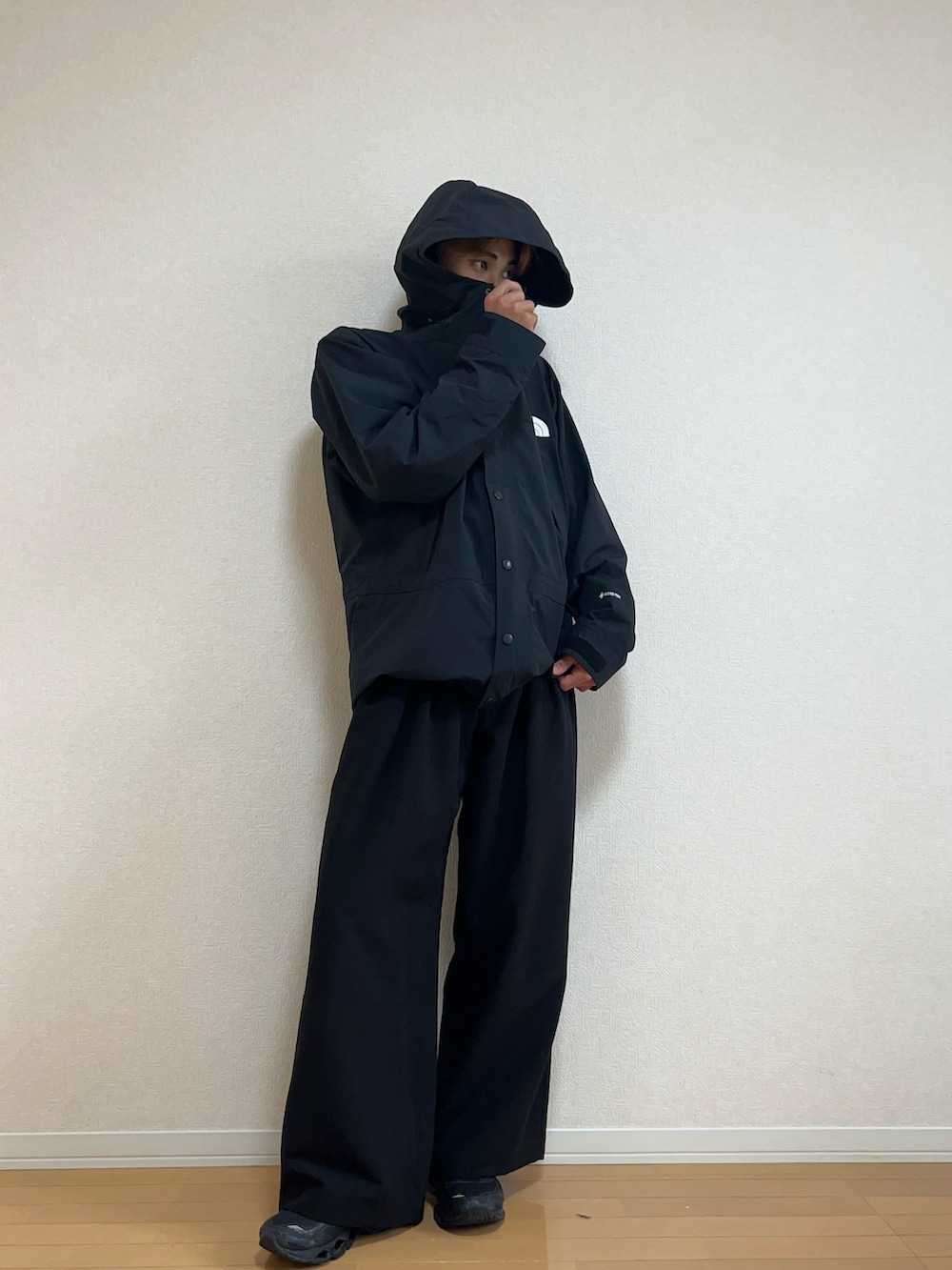 ブラック系のマウンテンパーカー、ブラック系のスラックス、ブラック系のスニーカーを着用したメンズの秋コーディネートの2枚目の写真