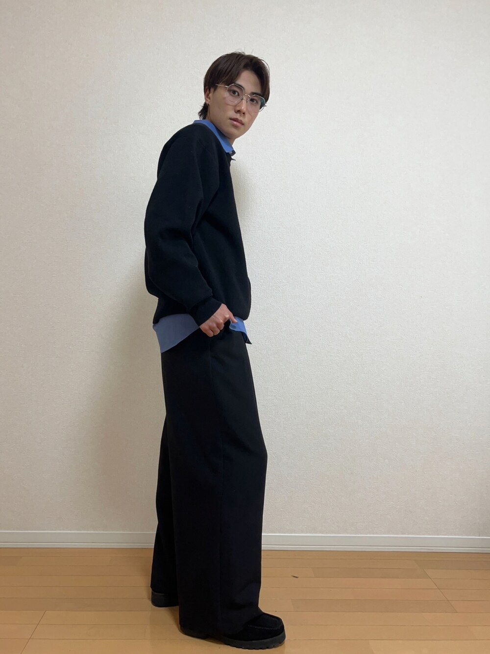 ブラック系のニット/セーター、ブルー系のシャツ/ブラウス、ブラック系のスラックスを着用したメンズの秋コーディネートの2枚目の写真