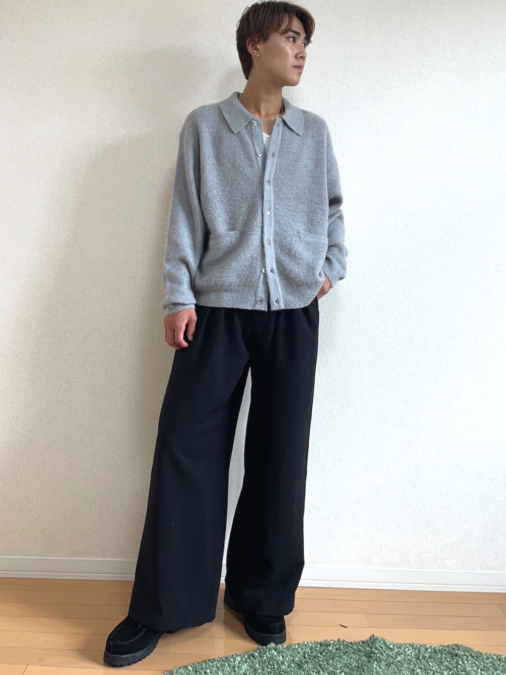 グレー系のニット/セーター、ブラック系のスラックス、ブラック系のモカシン/デッキシューズを着用したメンズの秋コーディネートの2枚目の写真