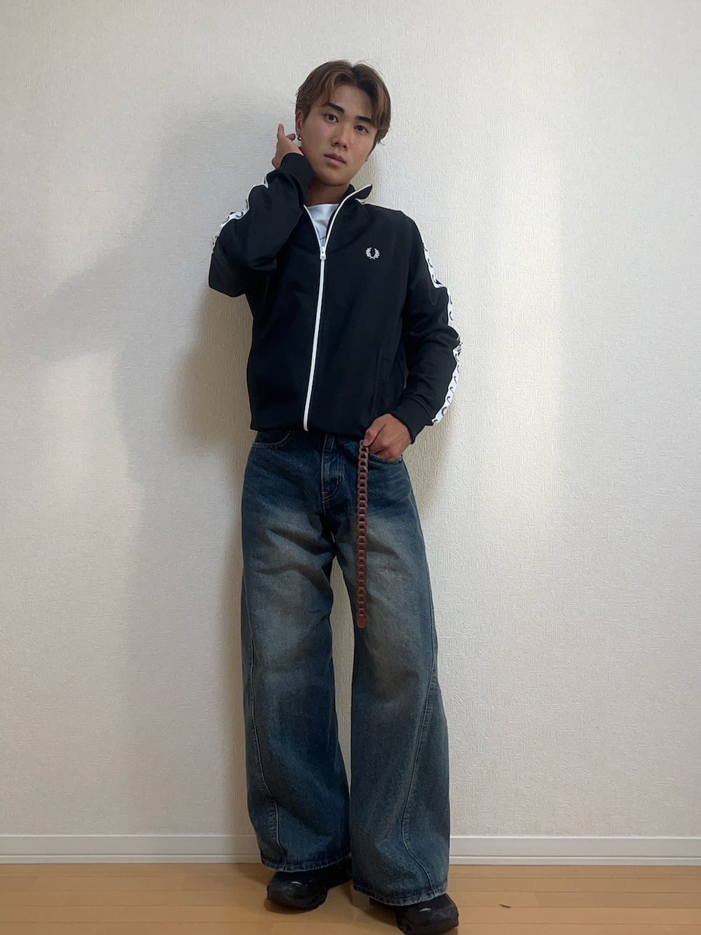 ブラック系のブルゾン、ブルー系のデニムパンツ、ブラック系のスニーカーを着用したメンズの秋コーディネートの2枚目の写真