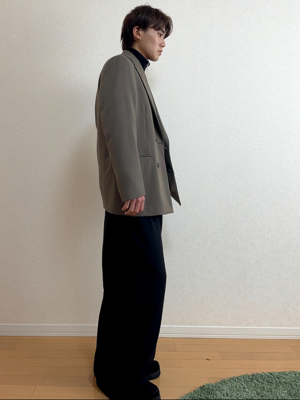 グリーン系のテーラードジャケット、ブラック系のニット/セーター、ブラック系のスラックスを着用したメンズの秋コーディネートの2枚目の写真