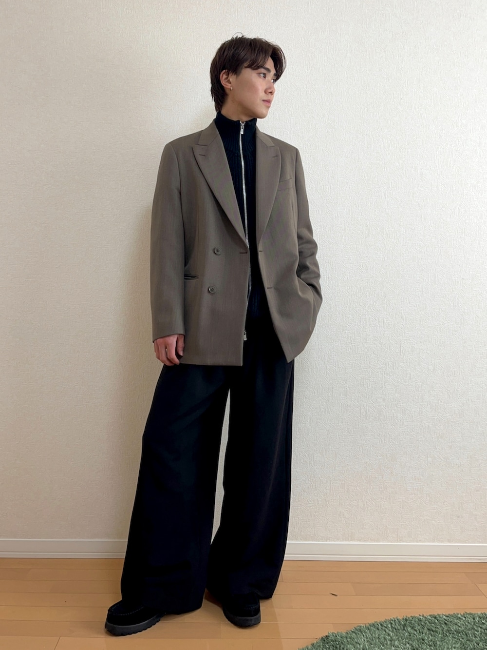 グリーン系のテーラードジャケット、ブラック系のニット/セーター、ブラック系のスラックスを着用したメンズの秋コーディネートの3枚目の写真