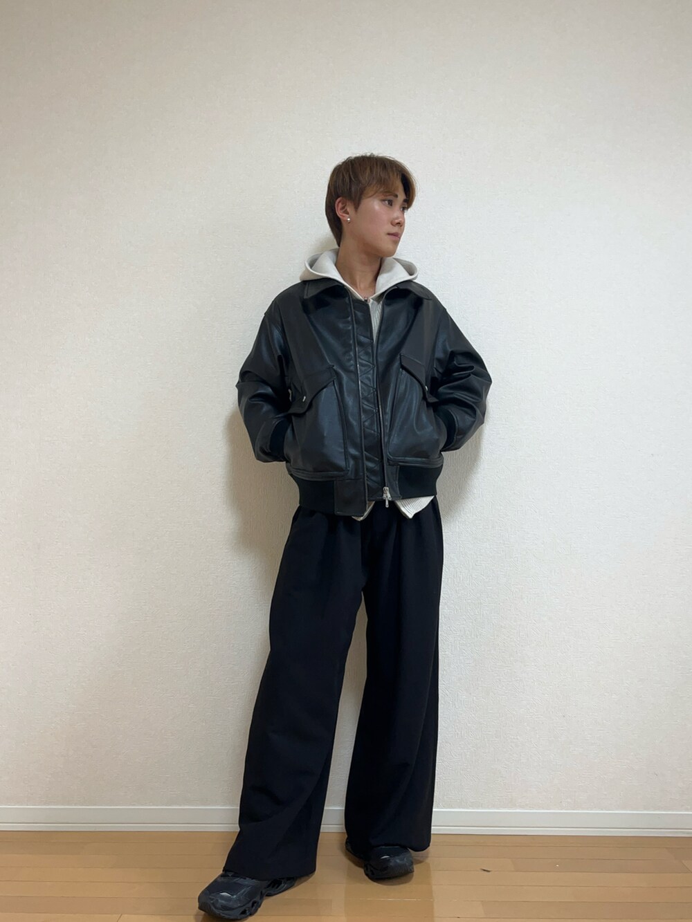 ブラック系のブルゾン、ホワイト系のニット/セーター、ブラック系のスラックスを着用したメンズの秋コーディネートの2枚目の写真