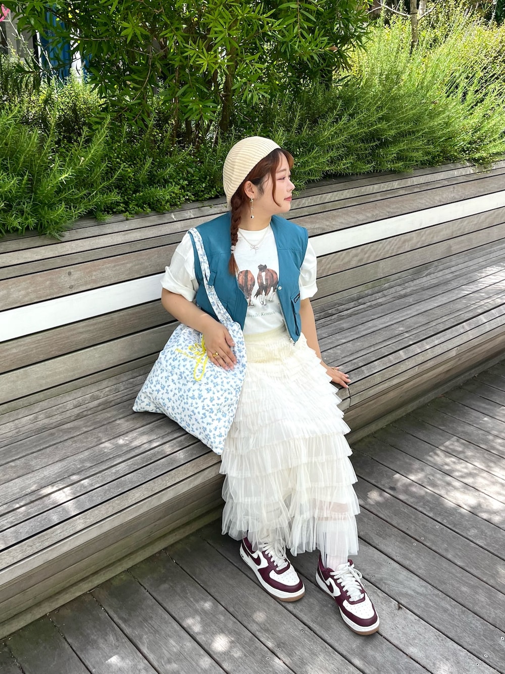 ブルー系のトートバッグ、ブルー系のベスト、ホワイト系のTシャツ/カットソーを着用したレディースの夏コーディネートの3枚目の写真