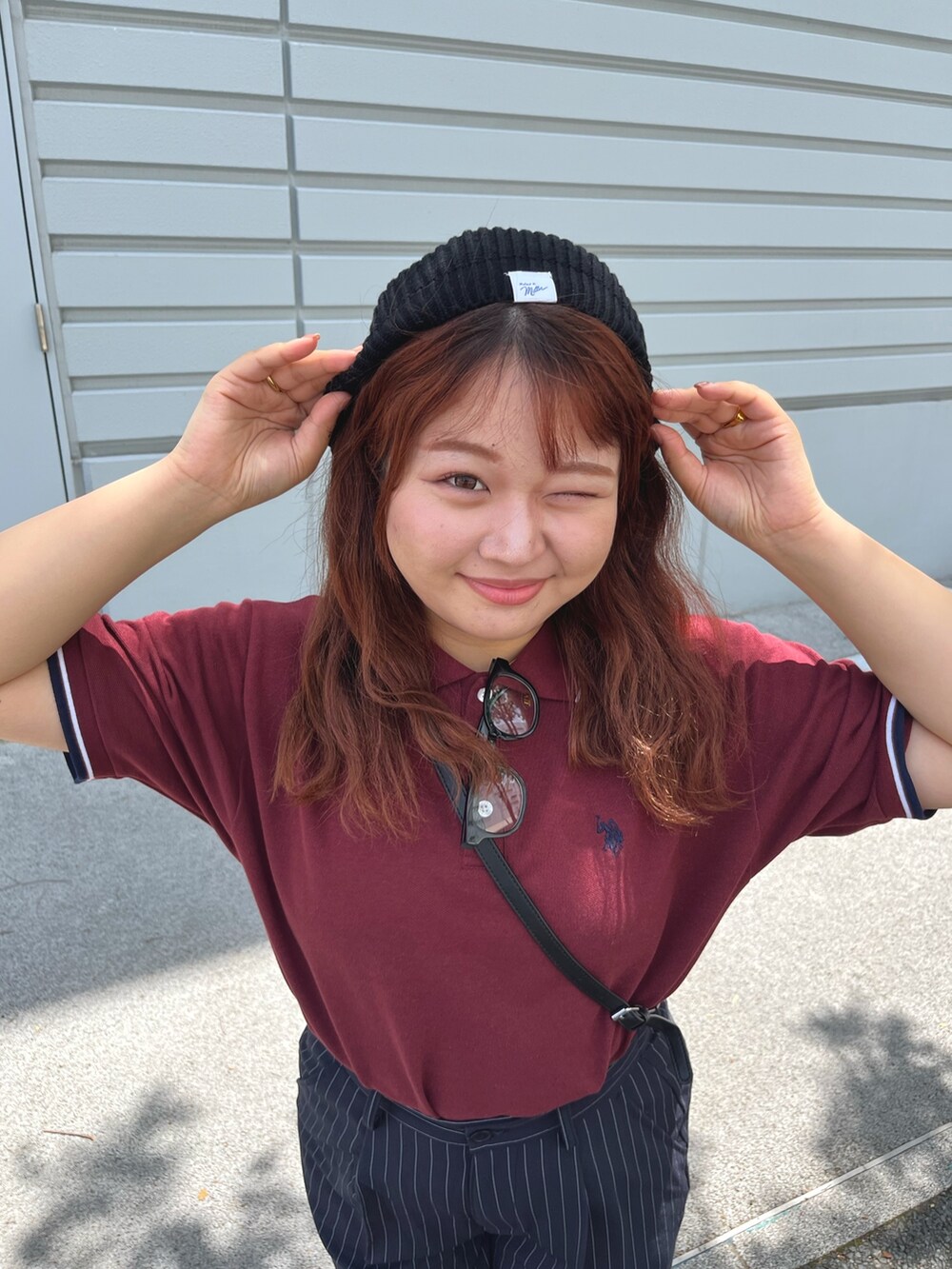 ブルー系のスラックス、レッド系のポロシャツ、ブラック系のハンチング/ベレー帽を着用したレディースの春コーディネートの3枚目の写真