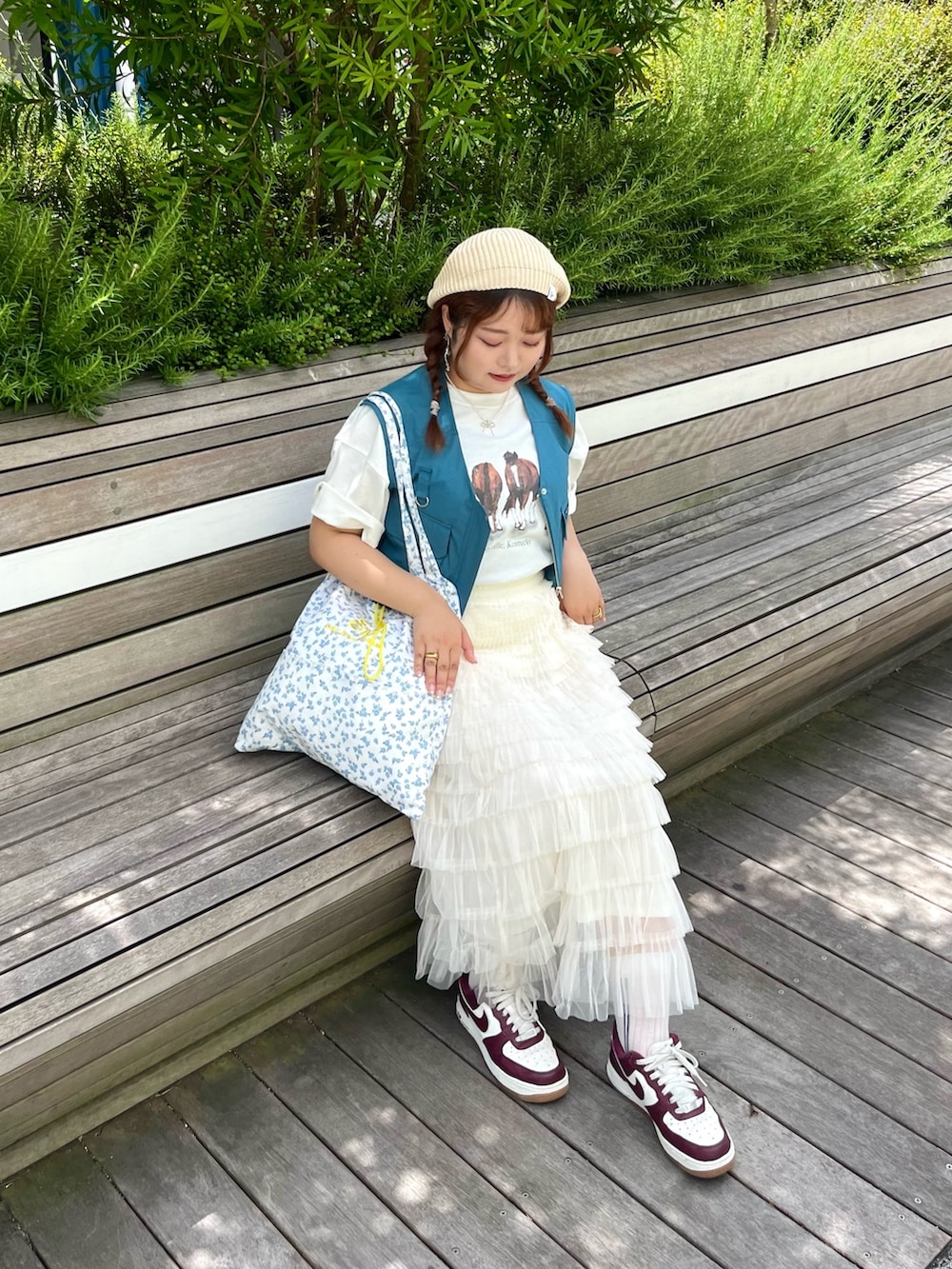 ブルー系のトートバッグ、ブルー系のベスト、ホワイト系のTシャツ/カットソーを着用したレディースの夏コーディネートの2枚目の写真