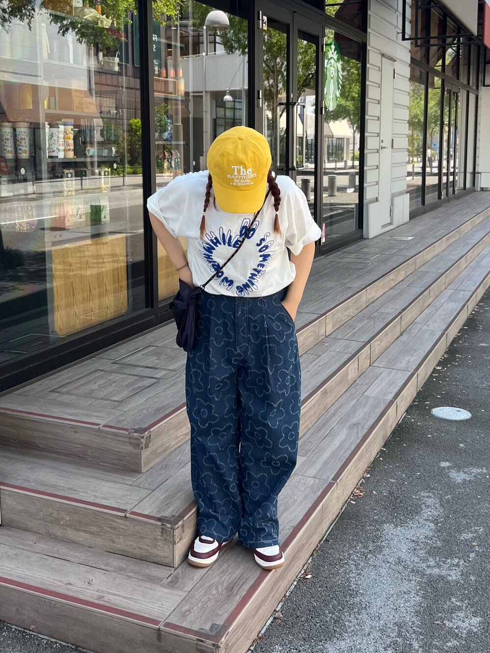 ブルー系のデニムパンツ、ホワイト系のTシャツ/カットソー、イエロー系のキャップを着用したレディースの春コーディネートの2枚目の写真