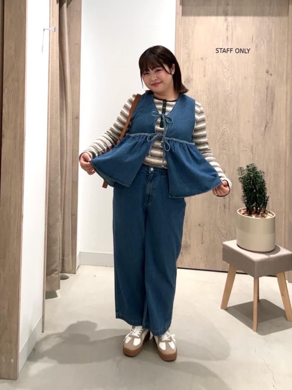 ブルー系のワンピース、ブラウン系のトートバッグ、ベージュ系のスニーカーを着用したレディースの春コーディネートの2枚目の写真