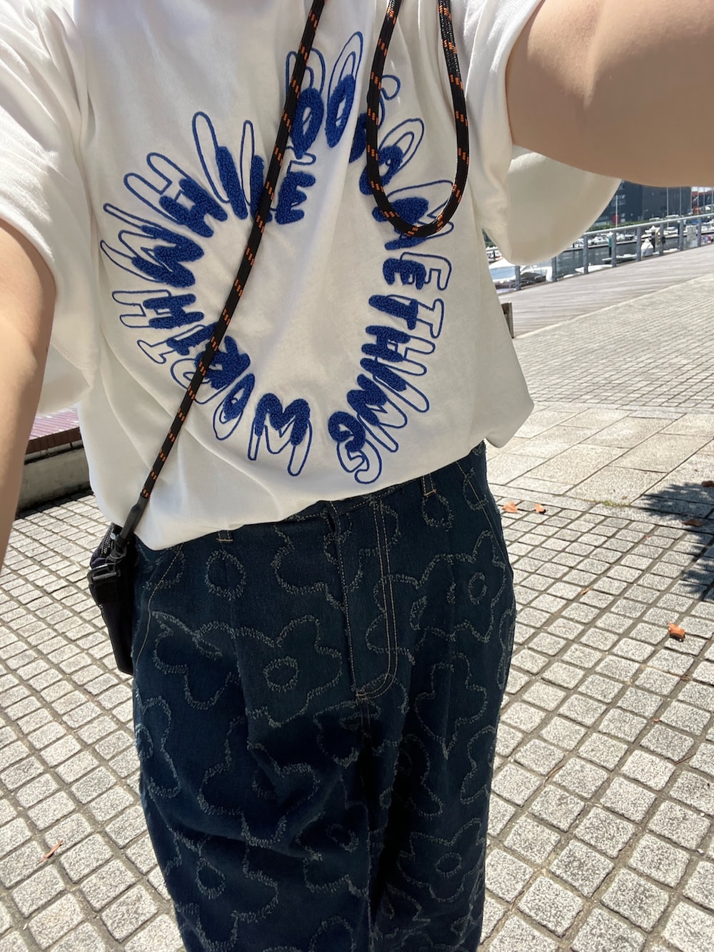 ブルー系のデニムパンツ、ホワイト系のTシャツ/カットソー、イエロー系のキャップを着用したレディースの春コーディネートの3枚目の写真