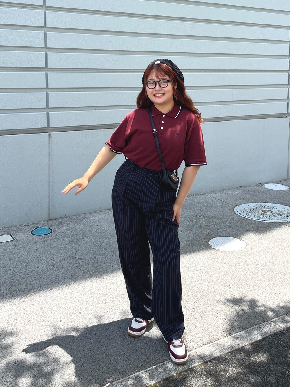 ブルー系のスラックス、レッド系のポロシャツ、ブラック系のハンチング/ベレー帽を着用したレディースの春コーディネートの2枚目の写真