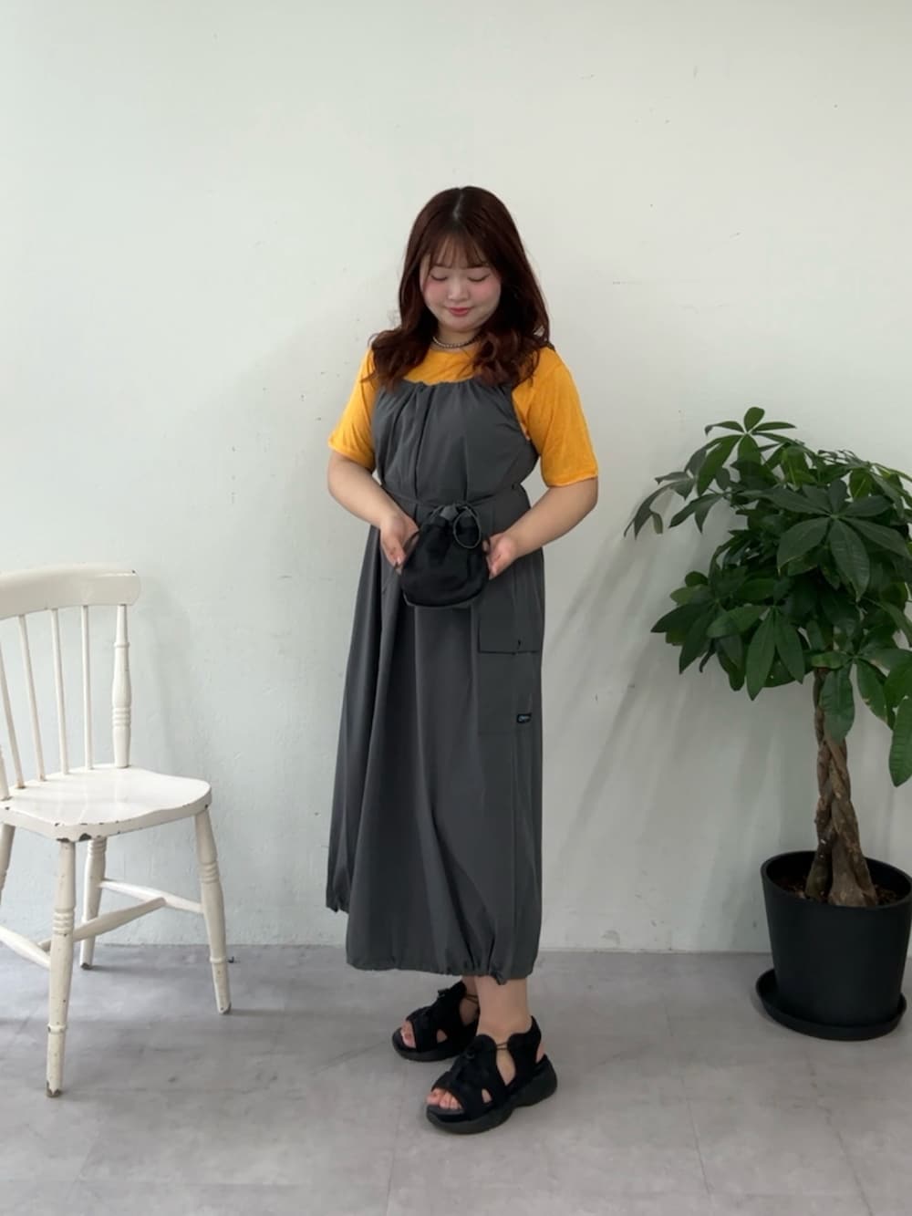 グレー系のワンピース、イエロー系のTシャツ/カットソー、ブラック系のサンダルを着用したレディースの夏コーディネートの2枚目の写真