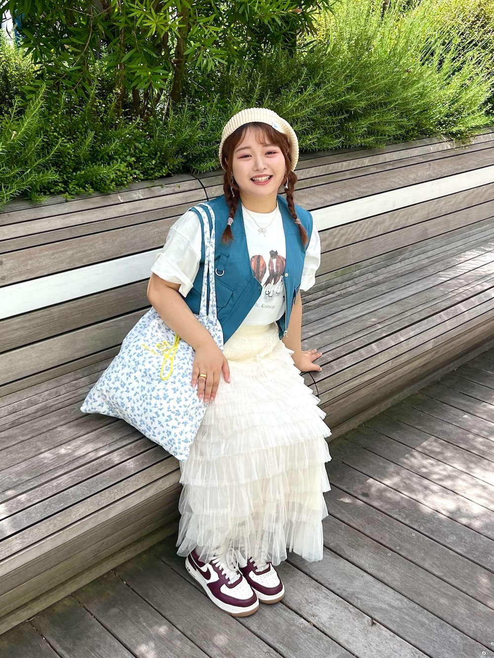 ブルー系のトートバッグ、ブルー系のベスト、ホワイト系のTシャツ/カットソーを着用したレディースの夏コーディネートの4枚目の写真