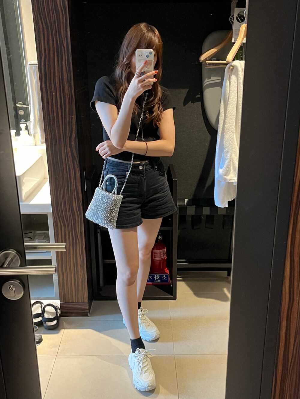 ブラック系のデニムパンツ、ブラック系のTシャツ/カットソー、ホワイト系のスニーカーを着用したレディースの夏コーディネートの2枚目の写真