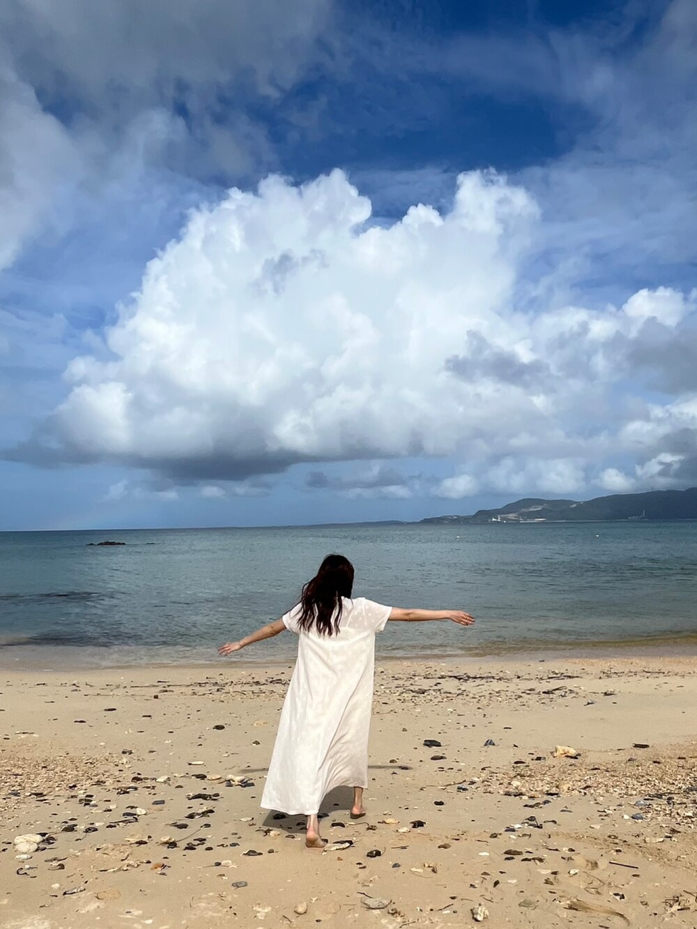 ホワイト系のワンピース、ホワイト系のサンダル、ベージュ系のショルダーバッグを着用したレディースの秋コーディネートの3枚目の写真