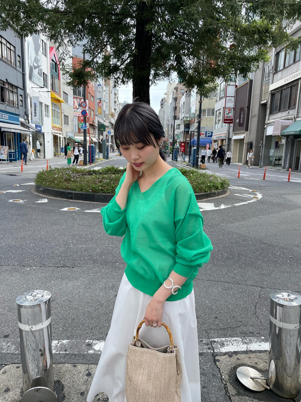 グリーン系のニット/セーター、ホワイト系のスカート、ベージュ系のバッグを着用したレディースの春コーディネートの4枚目の写真