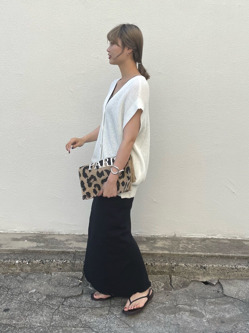 ブラック系のスカート、グレー系のタンクトップ、ホワイト系のベストを着用したレディースの春コーディネートの2枚目の写真