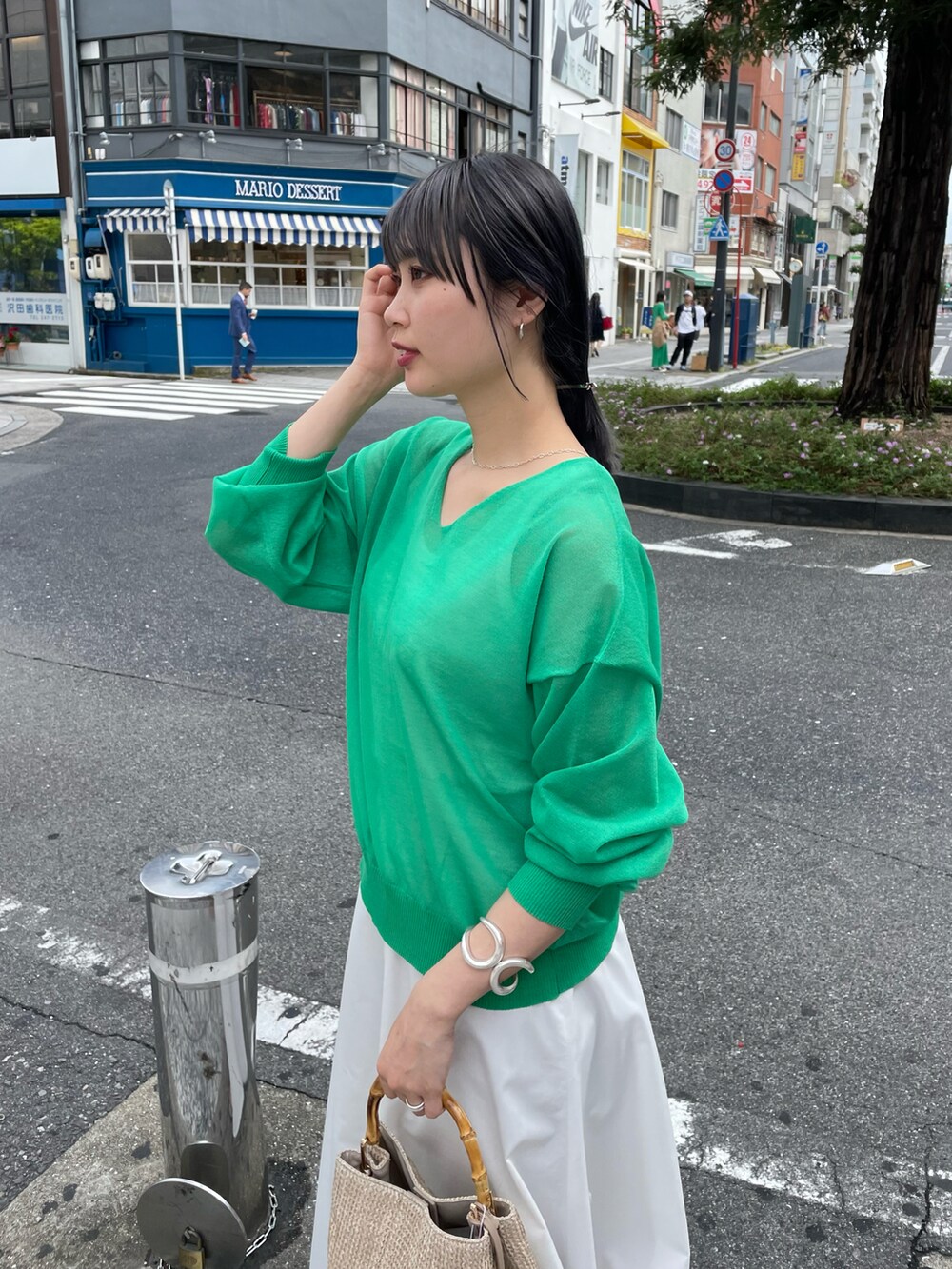 グリーン系のニット/セーター、ホワイト系のスカート、ベージュ系のバッグを着用したレディースの春コーディネートの3枚目の写真