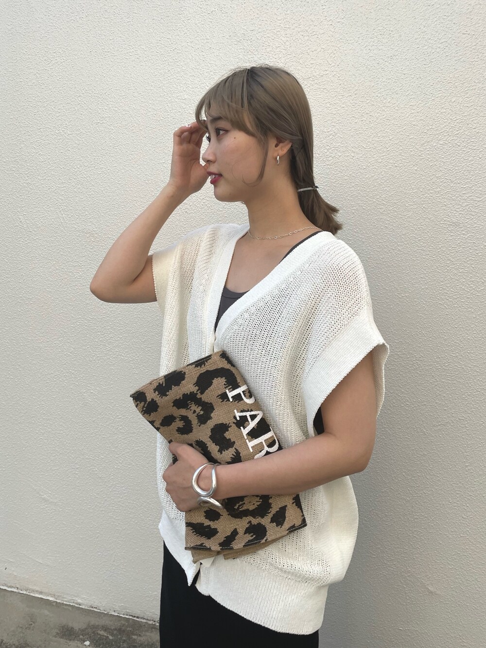 ブラック系のスカート、グレー系のタンクトップ、ホワイト系のベストを着用したレディースの春コーディネートの4枚目の写真