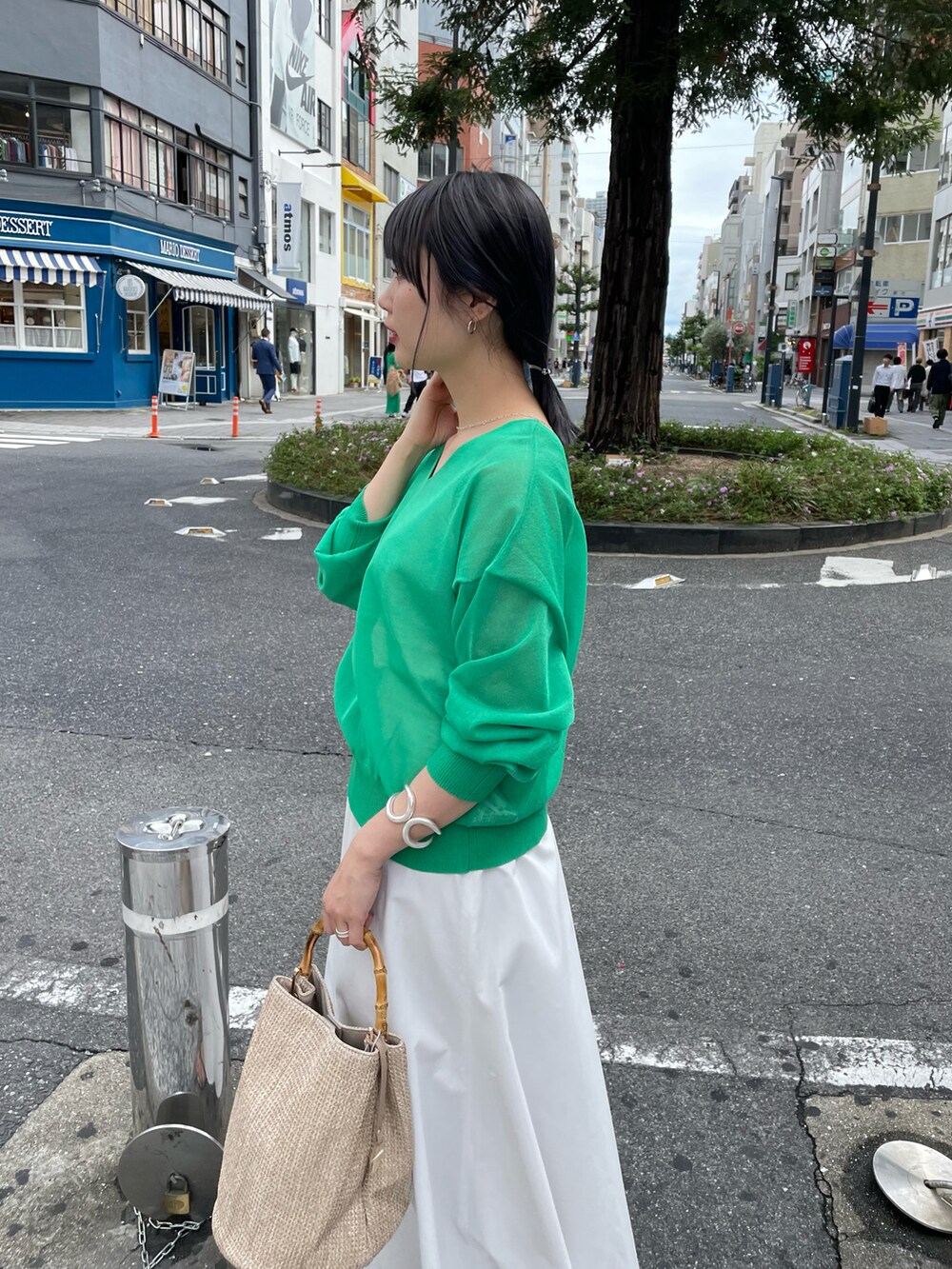 グリーン系のニット/セーター、ホワイト系のスカート、ベージュ系のバッグを着用したレディースの春コーディネートの5枚目の写真