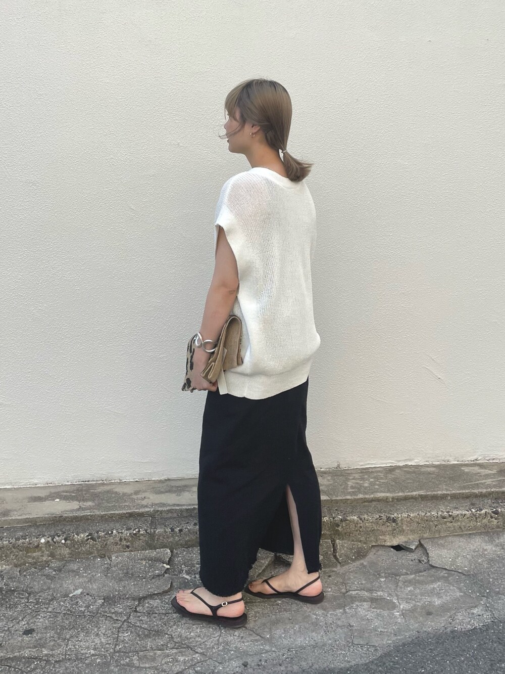ブラック系のスカート、グレー系のタンクトップ、ホワイト系のベストを着用したレディースの春コーディネートの3枚目の写真